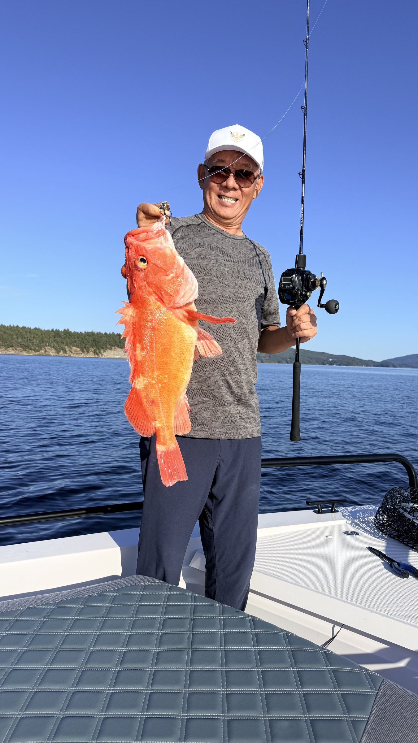 A guest on a fishing boat holding a red rockfish he caught